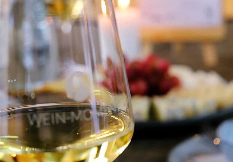 A close-up of a wine glass with the label 'WEIN-MO' and a blurred background with a candle. 3