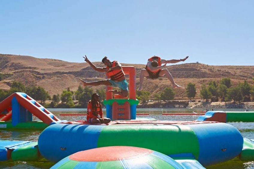 A water park with inflatable slides and a person jumping off a platform. 1