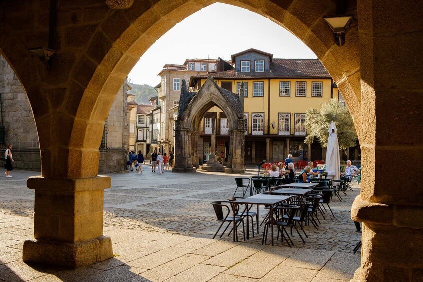 Un espace café en plein air agrémenté d’arches en pierre, de tables et de chaises, et entouré de bâtiments historiques. 4