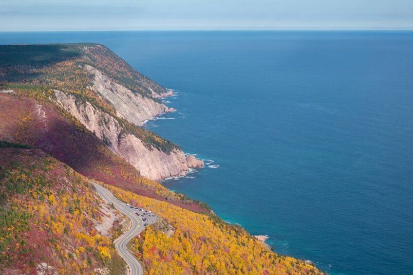 A coastal road winding through a forested cliffside with autumn foliage. 2