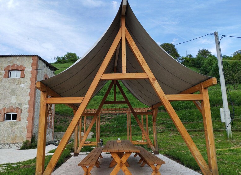 A wooden gazebo with a peaked roof and picnic tables. 5