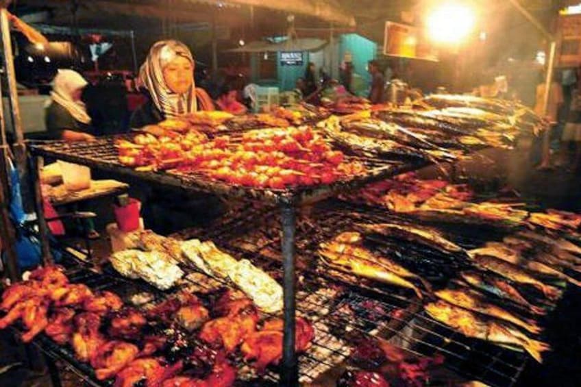 A market with various grilled seafood items displayed on racks. 2