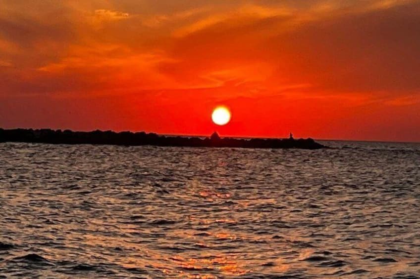 Solnedgang over et roligt hav med silhuetten af en bro i det fjerne. 5