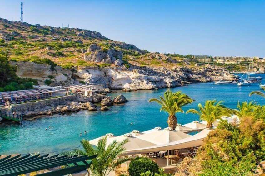 A coastal resort with clear blue waters, rocky cliffs, and a marina. 3