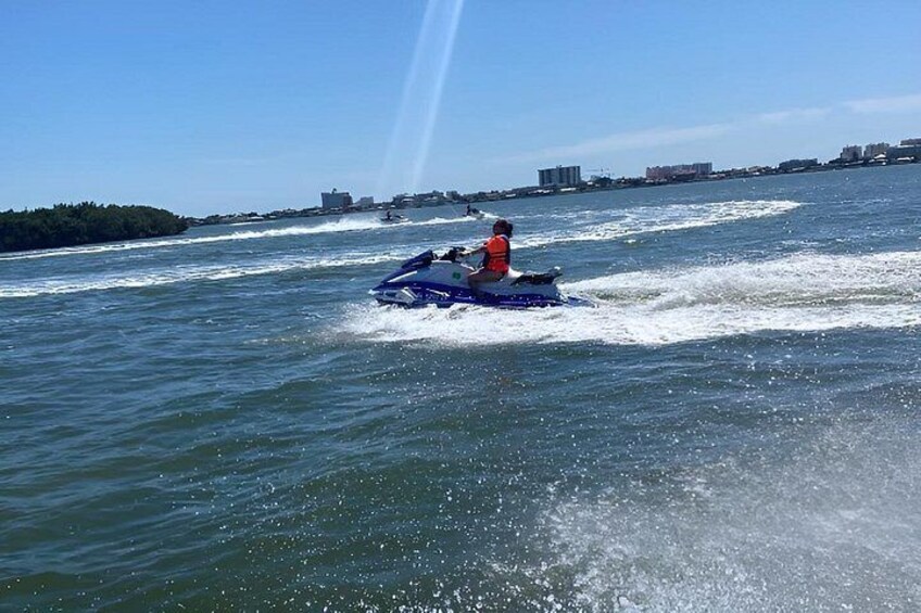 A person jet-skiing on a body of water with buildings in the background. 5