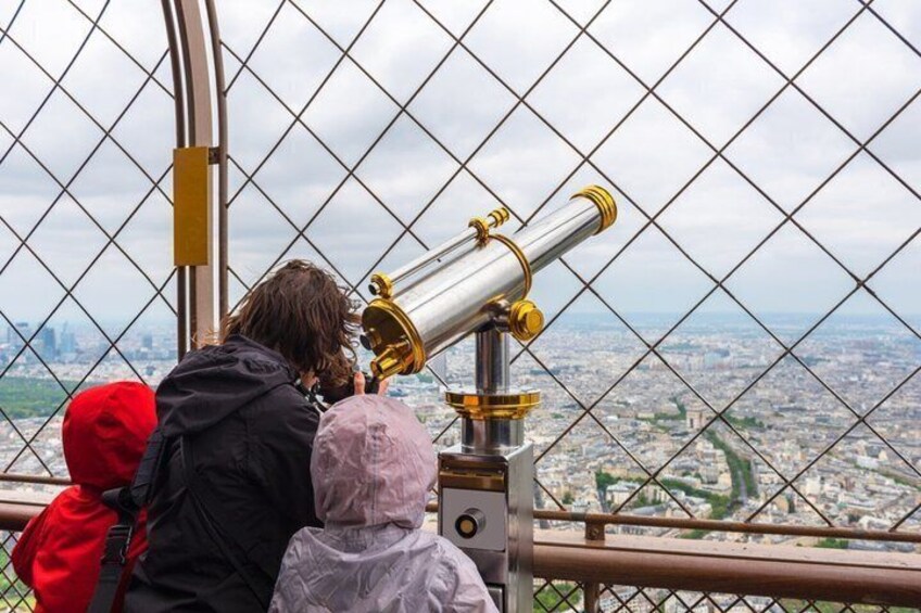 A person using a telescope with a cityscape in the background. 3