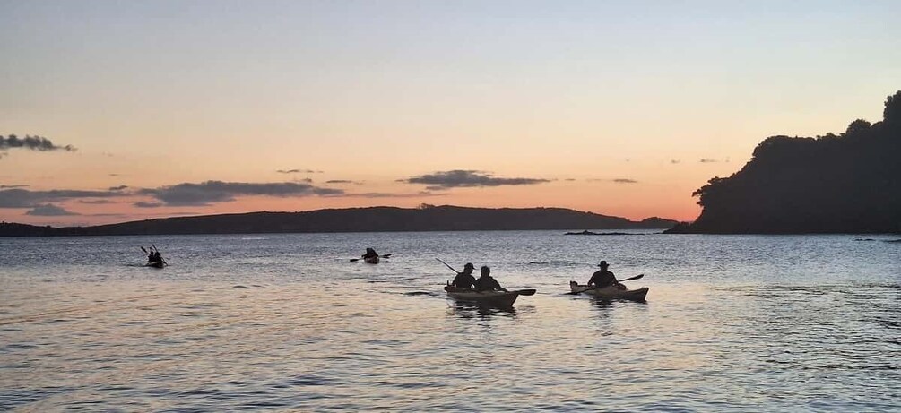 A calm lake with several boats and people fishing at sunset. 3