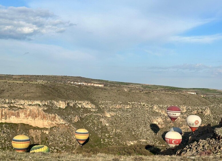 A landscape with a series of hot air balloons and a rocky cliff. 3