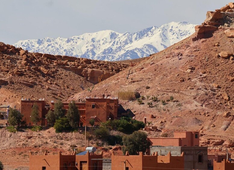 A mountainous landscape with snow-capped peaks in the background and traditional red-roofed buildings in the foreground. 5