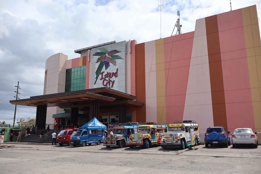 A colorful building with a palm tree logo and the name 'Island City.' There are various vehicles, including buses and cars, parked in front. 4