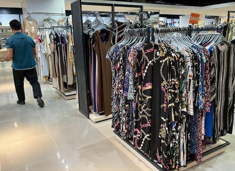 A clothing store with racks of dresses and a sale sign. 3