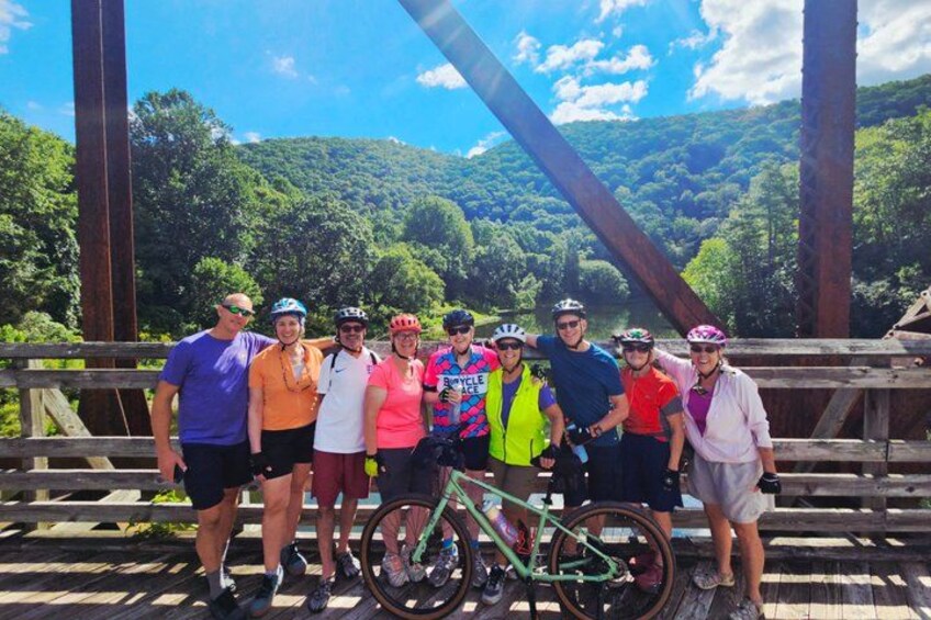 A group of people on a wooden bridge with a green bicycle in the foreground. 1