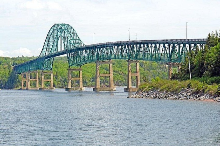 A large steel bridge with a distinctive arch over a river, surrounded by greenery. 3