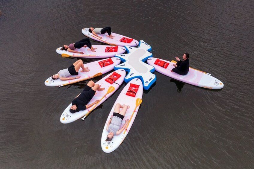 Personas en tablas de remo dispuestas en forma de estrella sobre el agua. 5