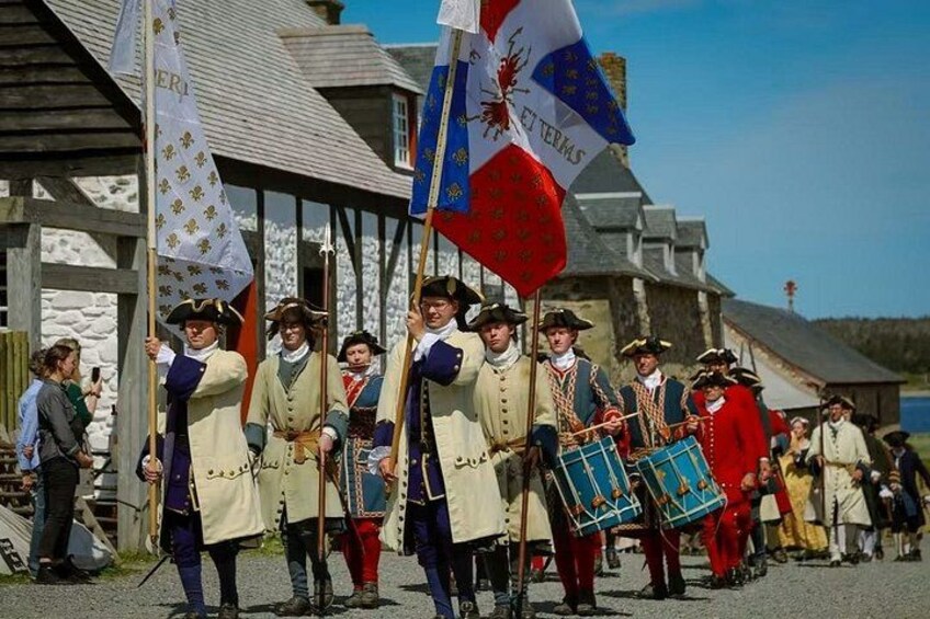 Un grupo de personas vestidas con trajes históricos marcha con banderas. 1