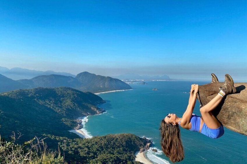 A person climbing a cliff overlooking a coastal landscape. 1