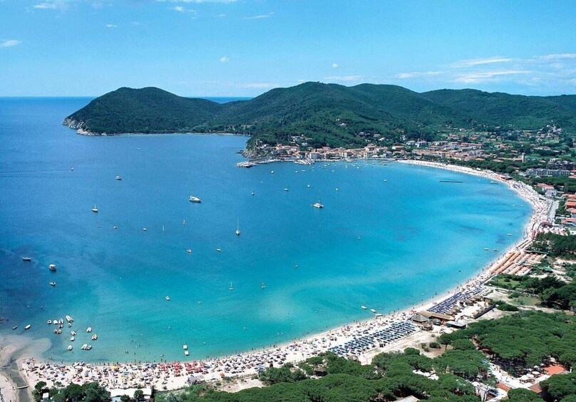 A coastal town with a beach, boats, and mountains. 4