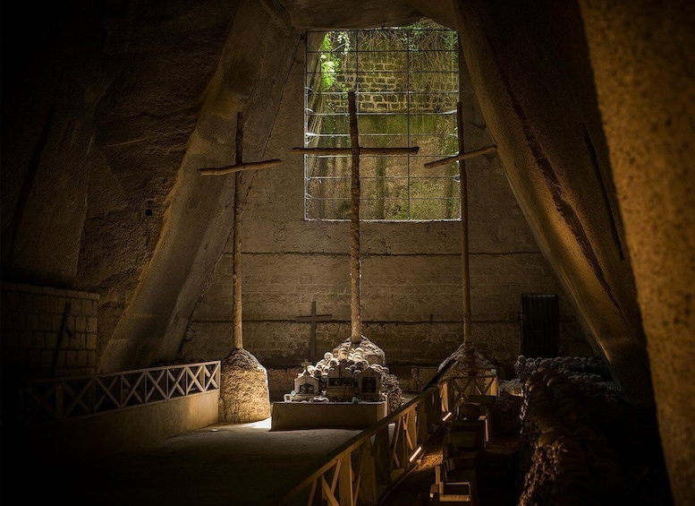 An attic church with a cross, altar, and a window with a view of greenery. 3