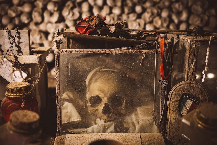 A rustic, weathered wooden box with a skull inside, surrounded by old bottles and a chain. 1