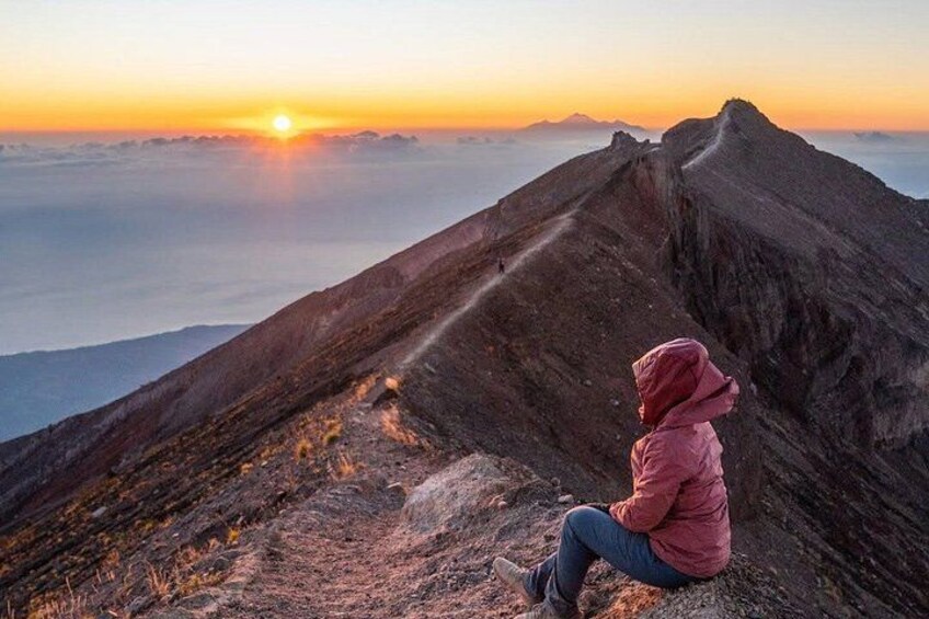 Une personne assise sur une crête montagneuse au coucher du soleil. 5