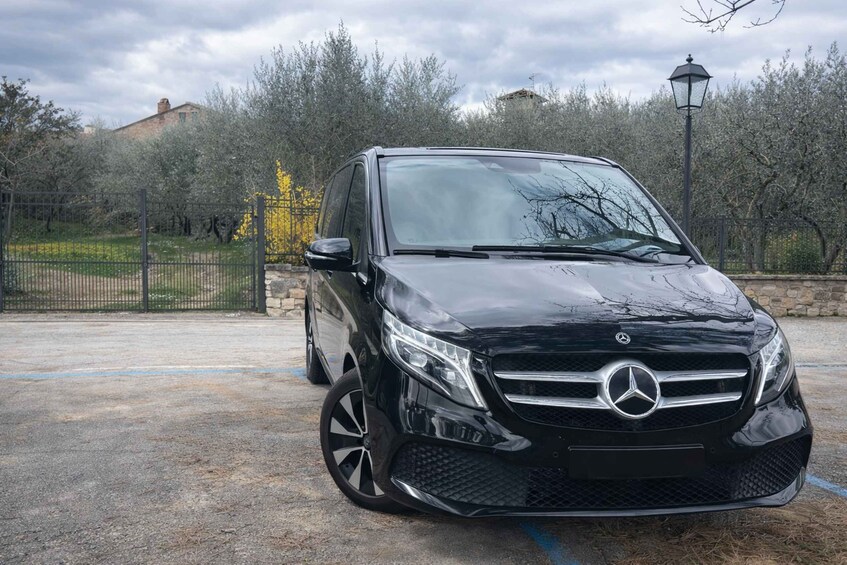 Musta Mercedes-Benz-merkkinen maasturi oli pysäköitynä parkkipaikalle, taustalla näkyi kivimuuri ja puita. 5