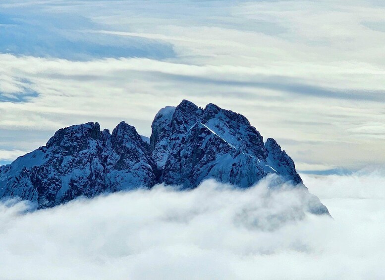 A snow-covered mountain range with sharp peaks and a layer of clouds below. 4