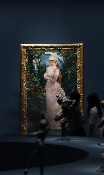 A painting of a woman in a dress holding an umbrella, framed in gold, with a dark blue background. 1