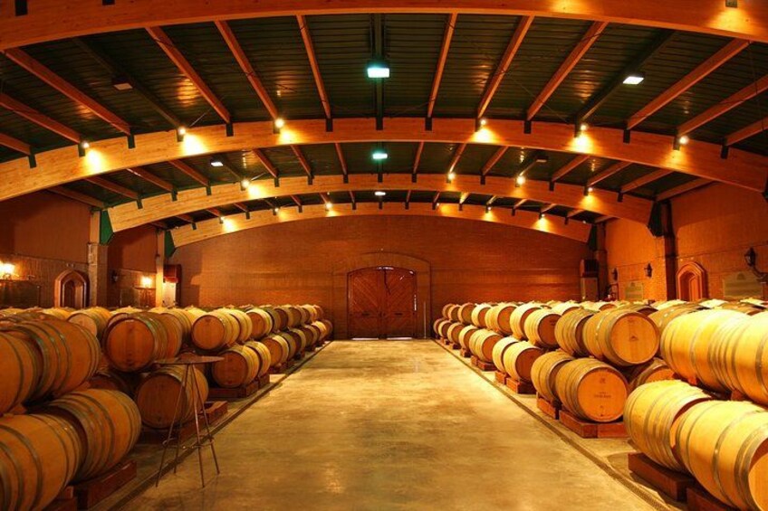 A large warehouse with wooden barrels arranged in rows. 4