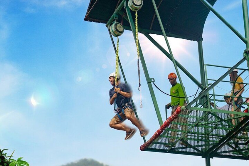Une personne pratiquant le saut à l’élastique, équipée d’un harnais de sécurité et de cordes, tandis qu’une autre personne se trouve sur une plateforme située au-dessus. 4