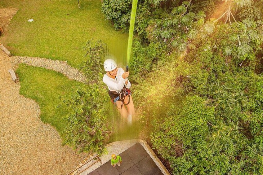 Una persona haciendo tirolesa por un paisaje exuberante y verde con abundante vegetación y un sendero despejado. 3