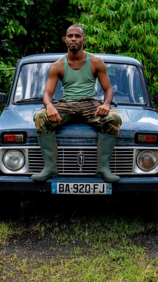 A man sitting on the hood of a vintage car with a license plate BA-920-FJ. 4