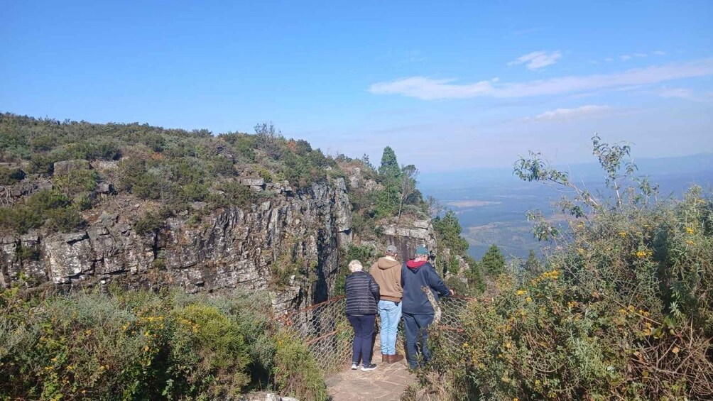 A group of people standing on a rocky cliff overlooking a valley. 4