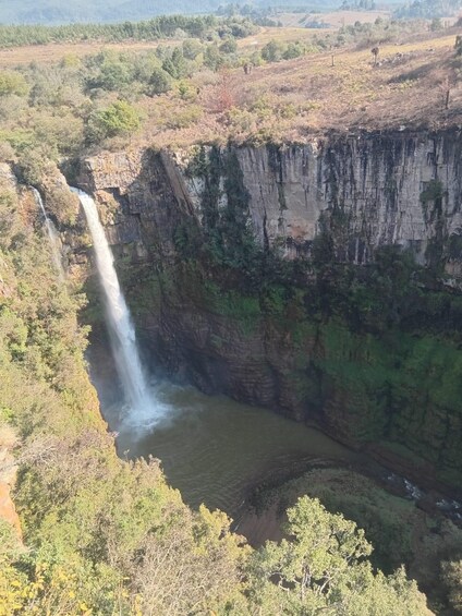 A waterfall cascading down a steep cliff surrounded by greenery. 2