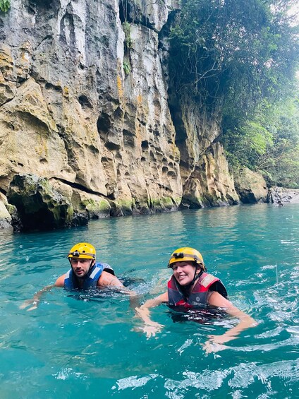 Two people in a river wearing helmets and life jackets. 5