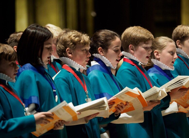 A group of people in teal robes with white collars, holding books, likely participating in a choir or musical performance. 4