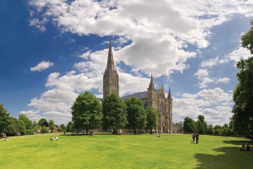 A large green field with a historic cathedral and two tall spires in the background. 1