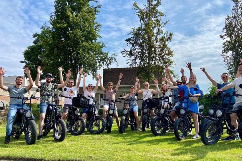 A group of people on bicycles in a grassy area with trees and a building in the background. 3