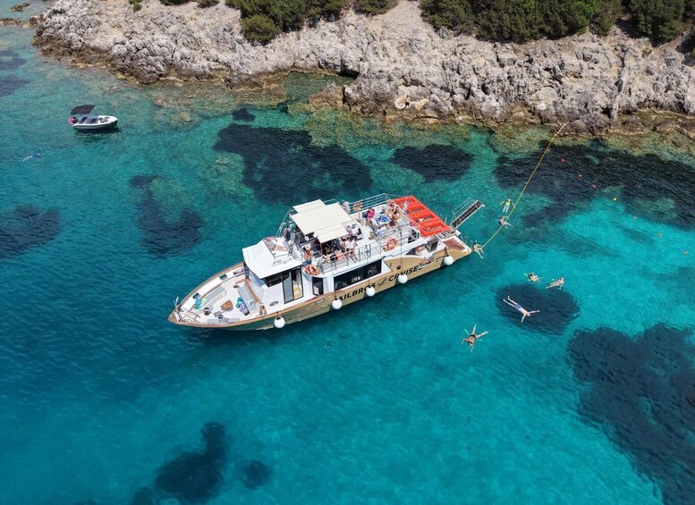 A boat with people on board and a smaller boat nearby in clear turquoise waters. 4