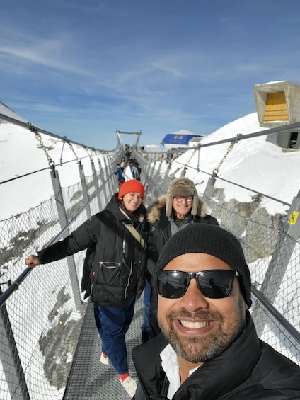 A snowy landscape with a metal bridge and a blue building in the background. 1