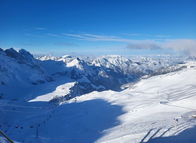 A snow-covered mountain range with ski slopes and a clear blue sky. 5