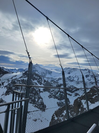 A snow-covered mountain range with a clear sky and a sun shining through the clouds. 4