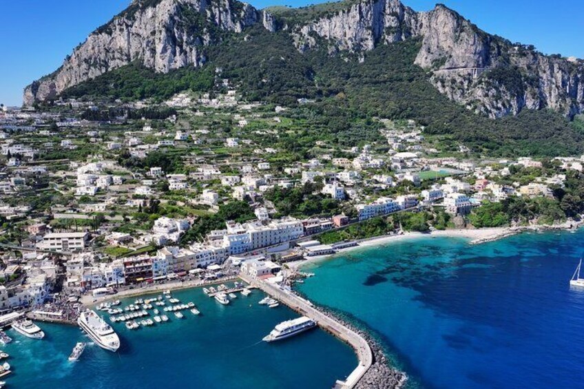 A coastal town with a marina, boats, and a mountainous backdrop. 3
