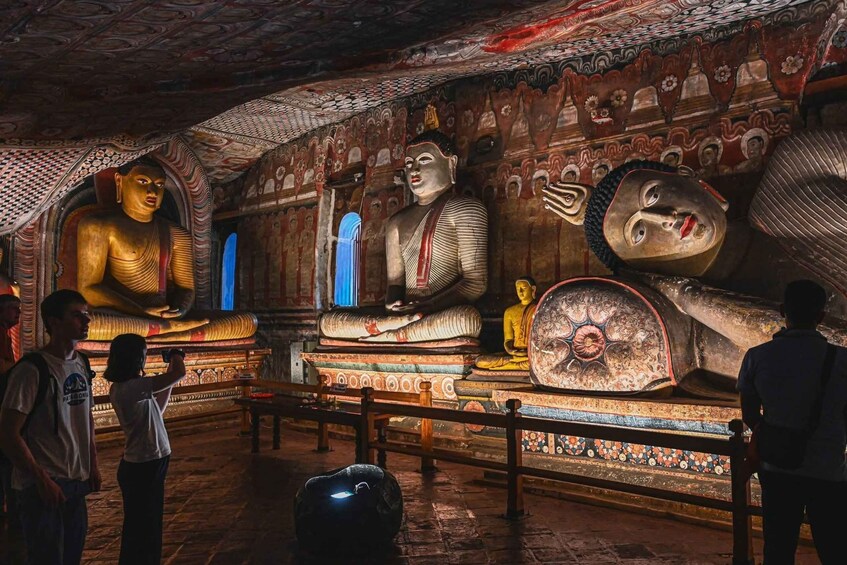 A temple interior with large Buddha statues and intricate wall carvings. 1
