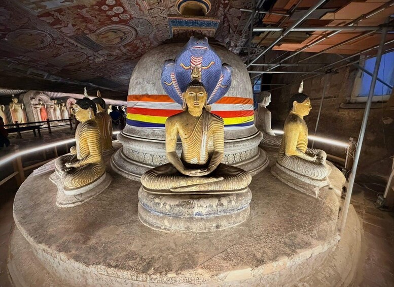 A large Buddha statue with a colorful striped background, surrounded by smaller seated Buddha statues. 2