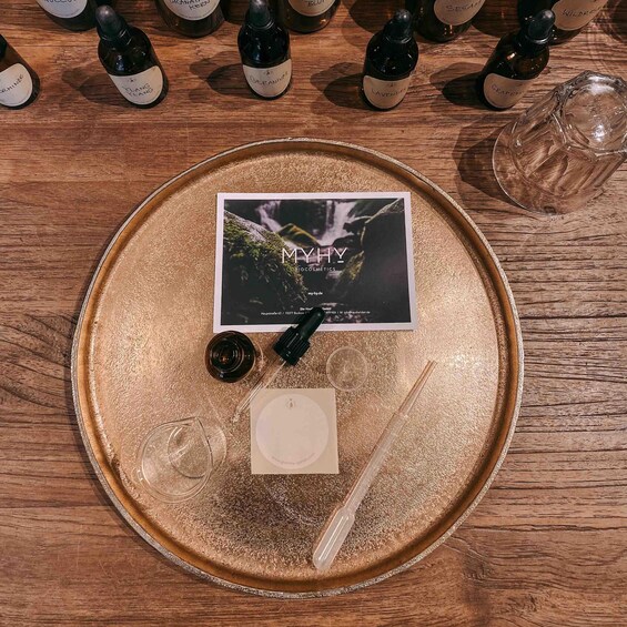 A tray with a card, a dropper, a small container, and a glass on a wooden surface. 5