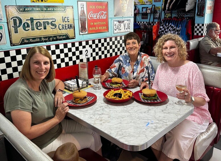 Three people dining at a booth with burgers, fries, and Coca-Cola. 1
