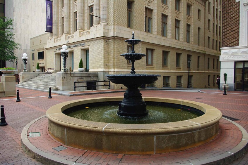 A historic building with a central fountain, a flag, and a staircase leading to the entrance. 1