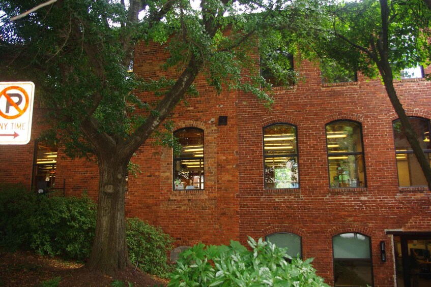 A brick building with arched windows and a tree in front. 3