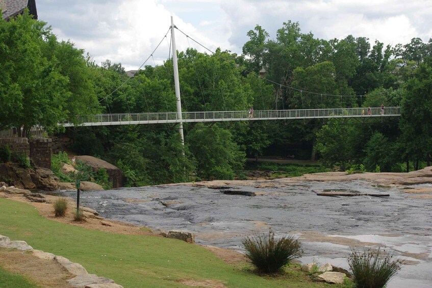 A suspension bridge over a river, surrounded by greenery and rocks. 2
