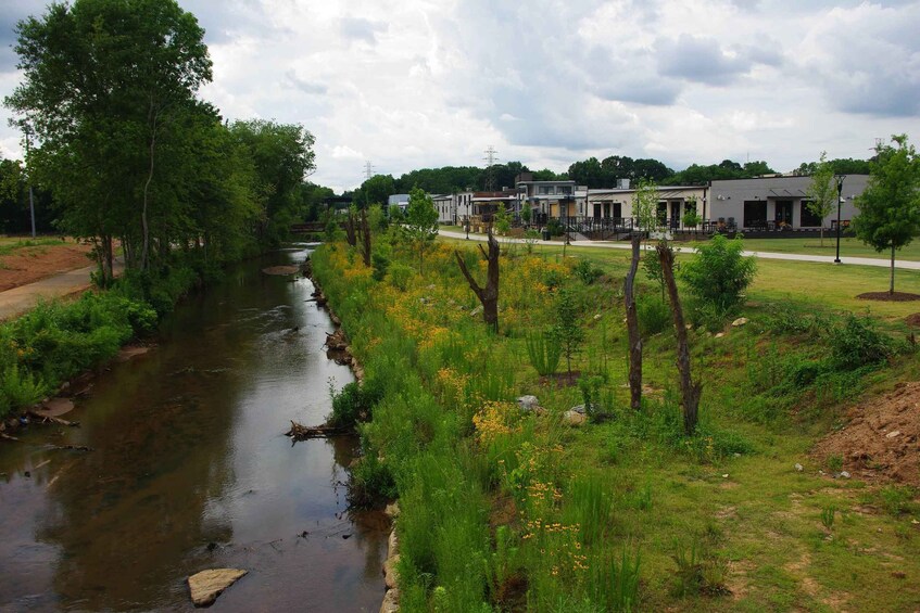 A river with a grassy bank, trees, and buildings in the background. 5